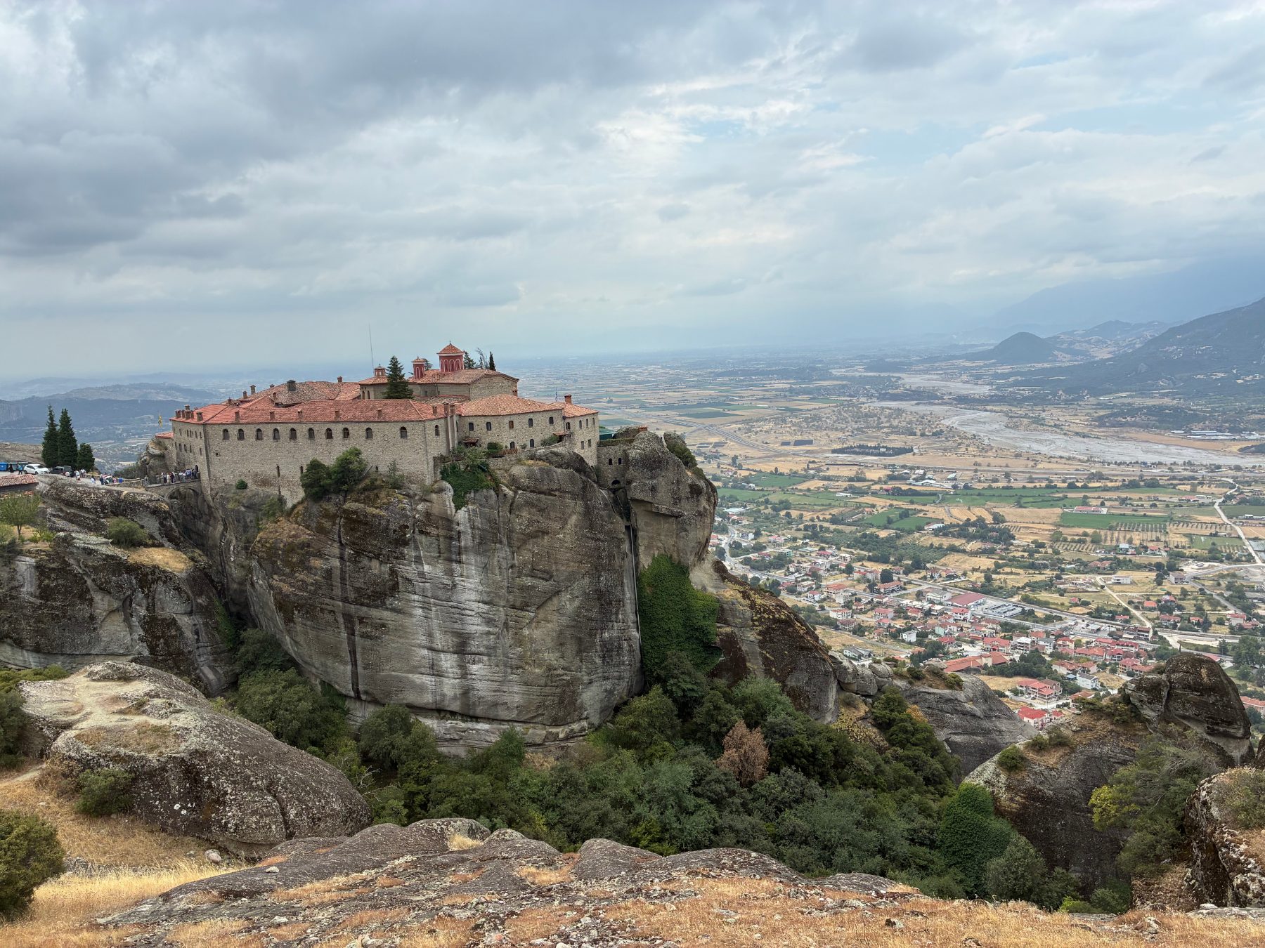 A monastery of Meteora perched on a sheer rock pillar, with the wide Thessalian valley beyond.