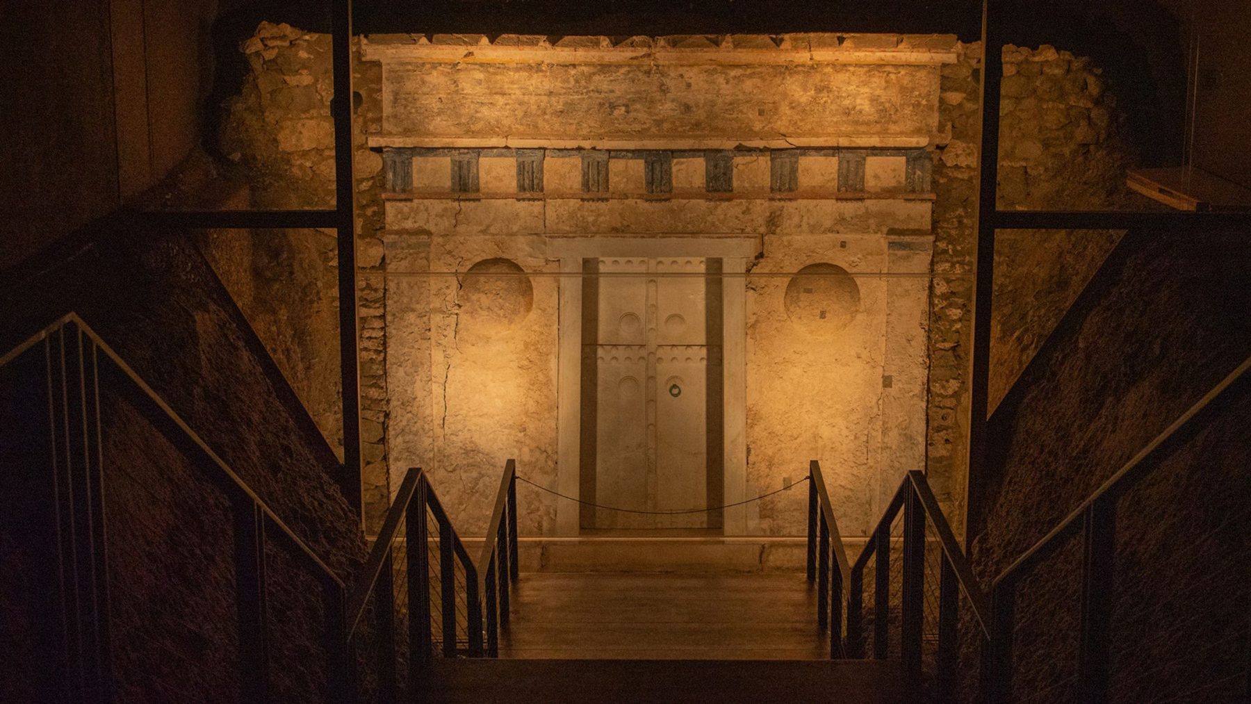 The painted façade of the royal tomb at Vergina, lit against the darkness of the burial mound.